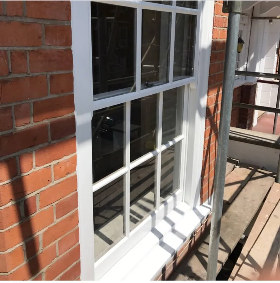 Restored white timber sash window with crisp paintwork on a red brick townhouse after refurbishment